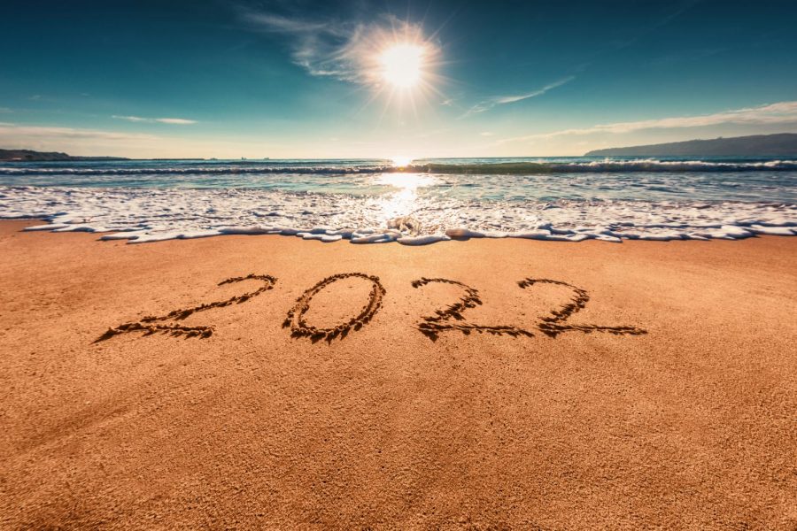 2022+written+in+the+sand+of+a+beach+with+the+ocean+and+summer+sky+in+the+background.